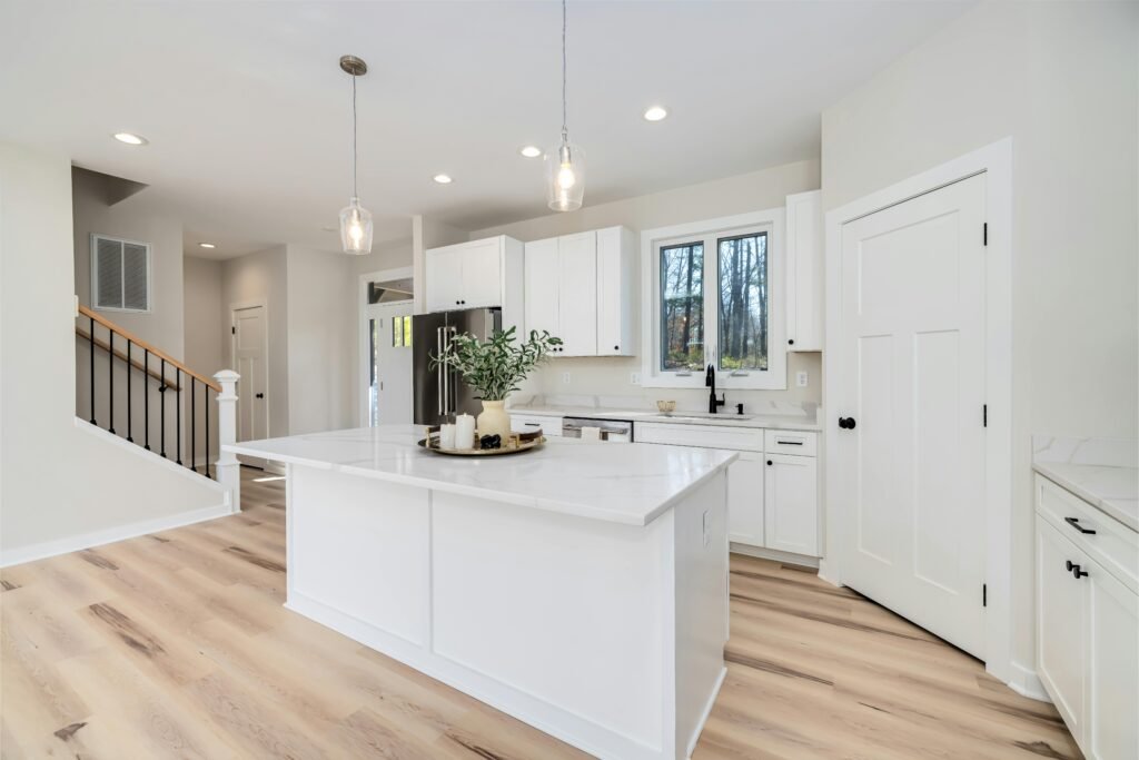 Bright modern kitchen featuring white cabinets and island, with minimalist decor.