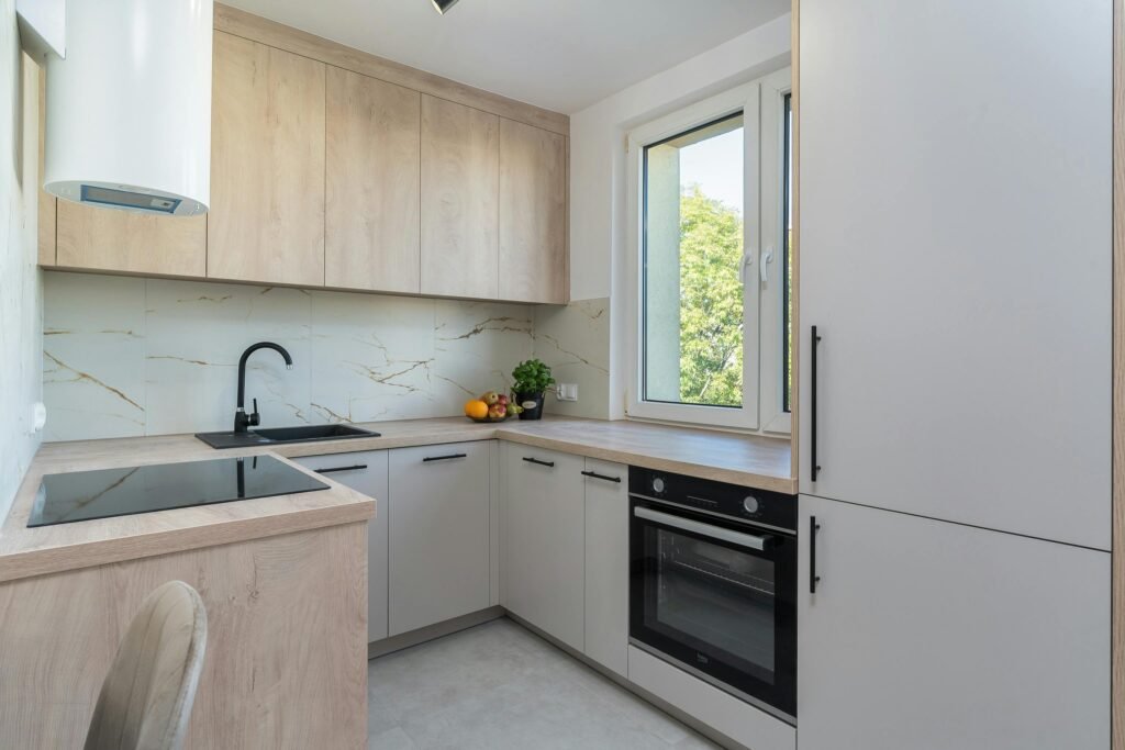 Bright minimalist kitchen with light wood cabinetry and modern appliances.