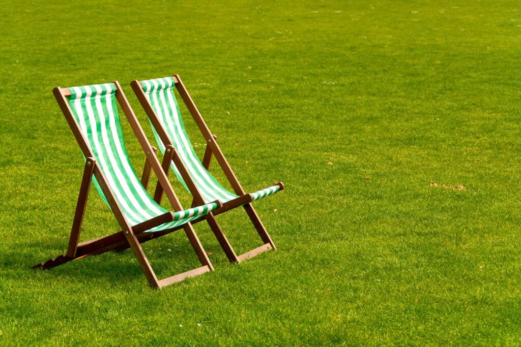 pexels-photo-29407197-29407197 Two striped deck chairs on a lush green lawn under bright sunlight, evoking relaxation.