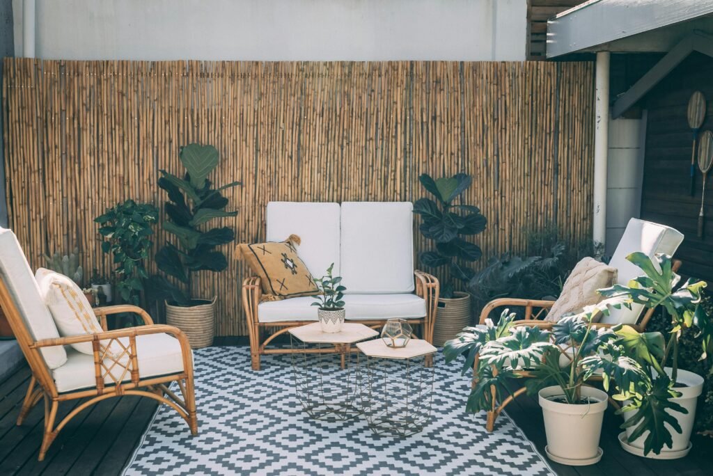 pexels-photo-6314322-6314322-1 Serene outdoor patio featuring rattan furniture, potted plants, and bamboo decor.